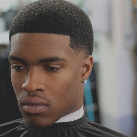 The high fade is a hairstyle characterized by short hair on the sides and back of the head, fading up to longer hair at or just above the temples. . Short low taper fade black male